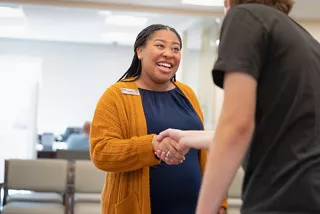 NF employee greeting a member with a handshake and a smile
